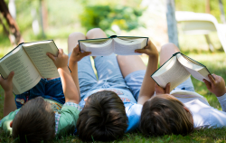 three kids reading books outside