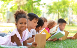 elementary kids reading books in grass