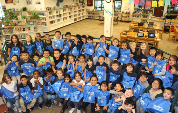 Group of students holding RIF bags reading literacy 
