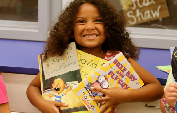 Girl student smiling and holding three RIF books