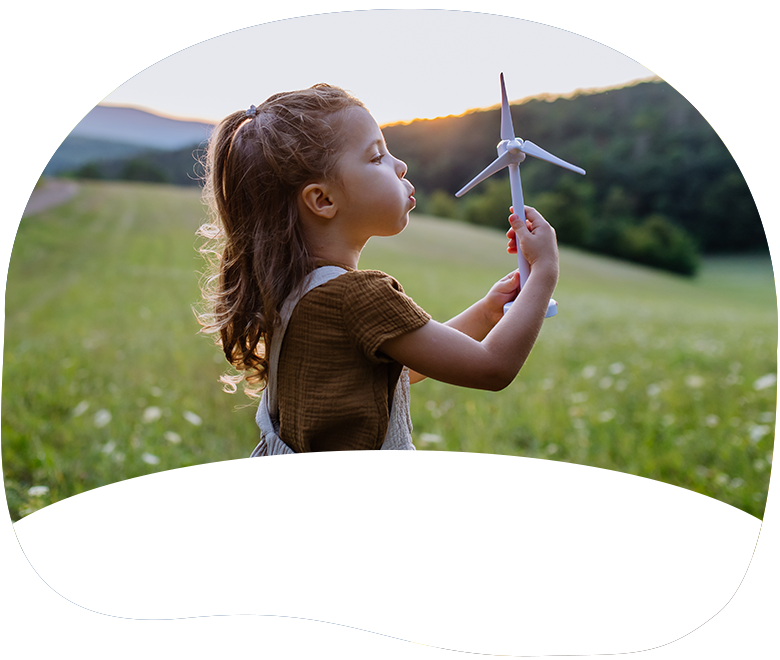 A young girl holds a toy airplane while standing in a field of grass.