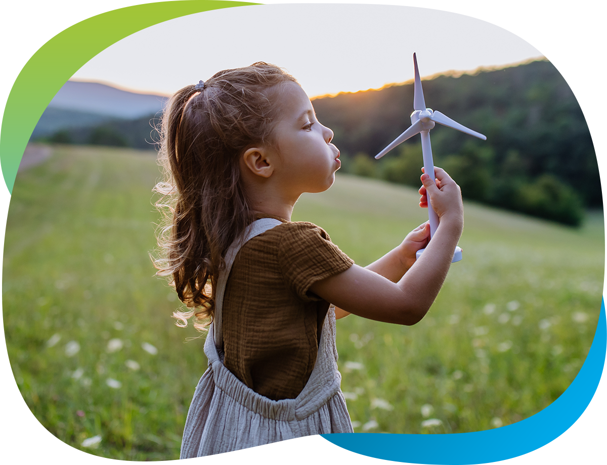 A young girl holds a toy airplane while standing in a field of grass.